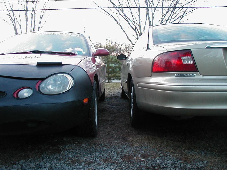 Front of red car with cover, next to tan car's rear