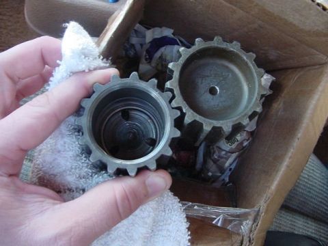 1971 Ford Bronco - A hand holds one of two metal sprockets, with the other resting in a cardboard box.