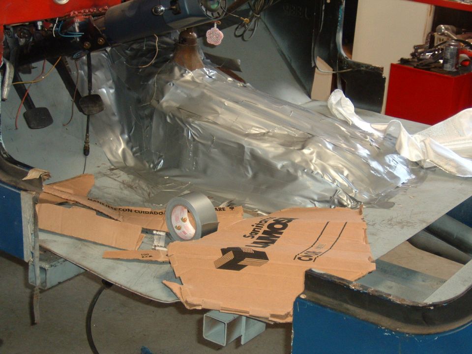 Stripped Jeep interior with tunnel masked in silver tape, cardboard template and duct tape roll on bare floor