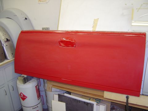 1978 Ford Bronco - A red truck tailgate is shown in a workshop setting, possibly awaiting installation or repair.
