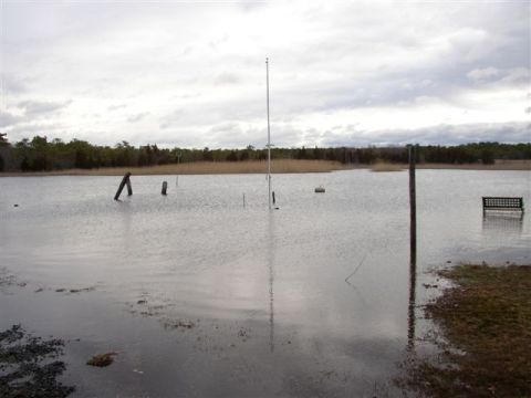 1995 Ford Bronco - Storm flooding has submerged a waterfront lawn, leaving a partly sunken park bench, a flagpole and wooden pilings standing in still floodwa…
