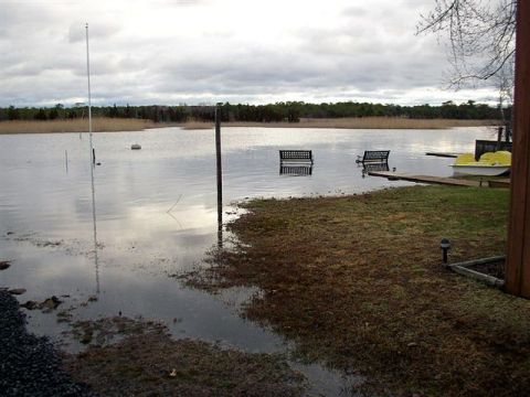 1995 Ford Bronco - Backyard flooding has submerged benches and a small boat, with a cloudy sky overhead.