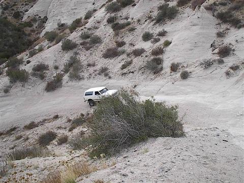 1988 Ford Bronco - White 1988 Ford Bronco navigates a dusty trail through a canyon.