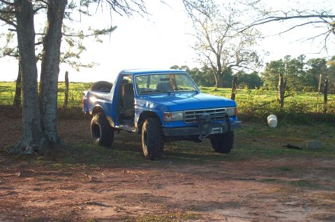 1987 Ford Bronco - This blue 1987 Ford Bronco features a winch and off-road tires, suggesting it's prepared for terrain.