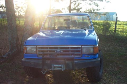 1987 Ford Bronco - A blue 1987 Ford Bronco is seen from the front, equipped with a winch and 4x4 badging.