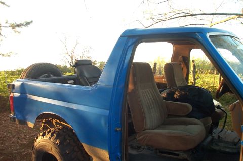 1987 Ford Bronco - Interior view of a blue Ford Bronco with brown seats and a spare tire visible in the cargo area.
