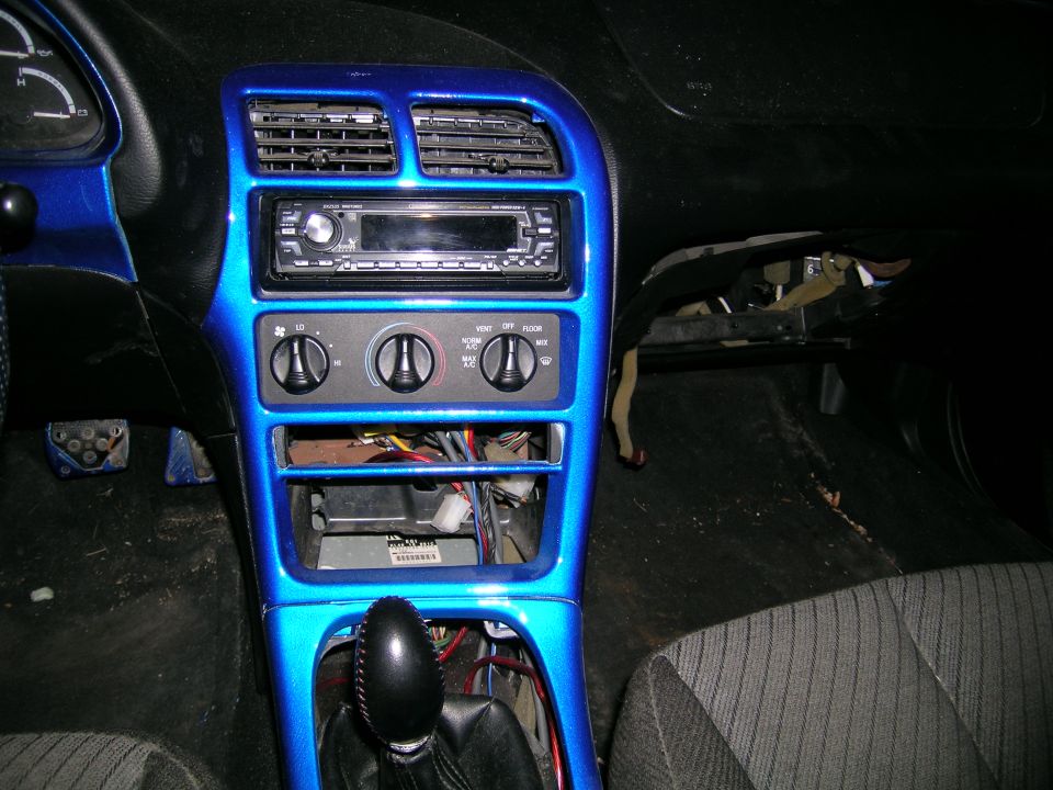 Car interior dashboard with custom blue paint, aftermarket stereo, and exposed wiring