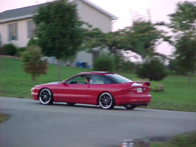 Red 1994 Ford Probe driving on a road, 3q-front view