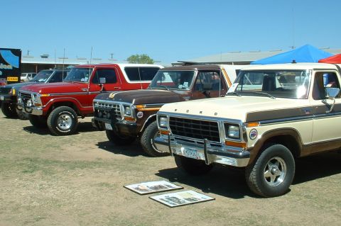 1978 Ford Bronco - A lineup of vintage Ford Broncos and trucks are displayed outdoors under a clear blue sky.