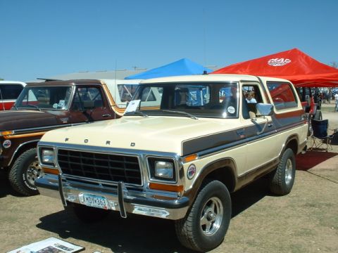 1978 Ford Bronco - A 1978 Ford Bronco is displayed outdoors next to another truck, with tents providing shade.
