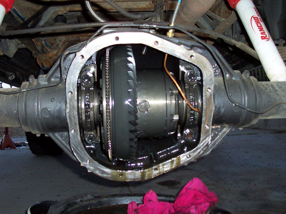 Differential housing opened to show gears and internal components. Red rags and a drain pan are visible below