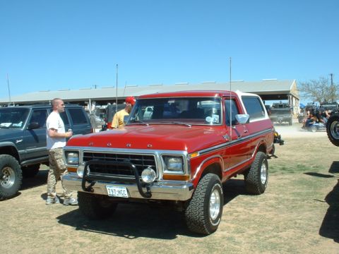 1978 Ford Bronco - A red 1978 Ford Bronco is parked in a lot with other vehicles under a clear blue sky.