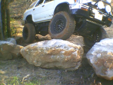 1991 Mazda Navajo - A white off-road SUV navigates a rocky terrain, its tires gripping the stones.