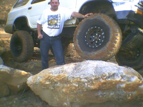 1991 Mazda Navajo - A man poses with a white SUV equipped with large off-road tires, navigating rocky terrain.