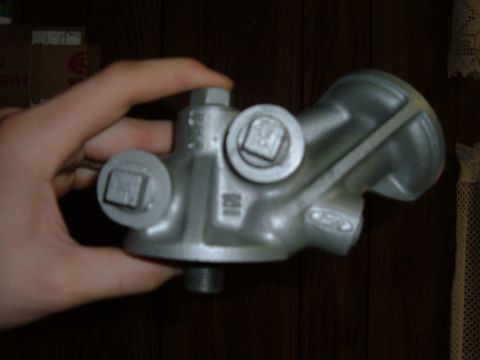 1985 Ford F-150 - A hand holds a silver metal engine oil filter housing, with "FORD" stamped on its side.