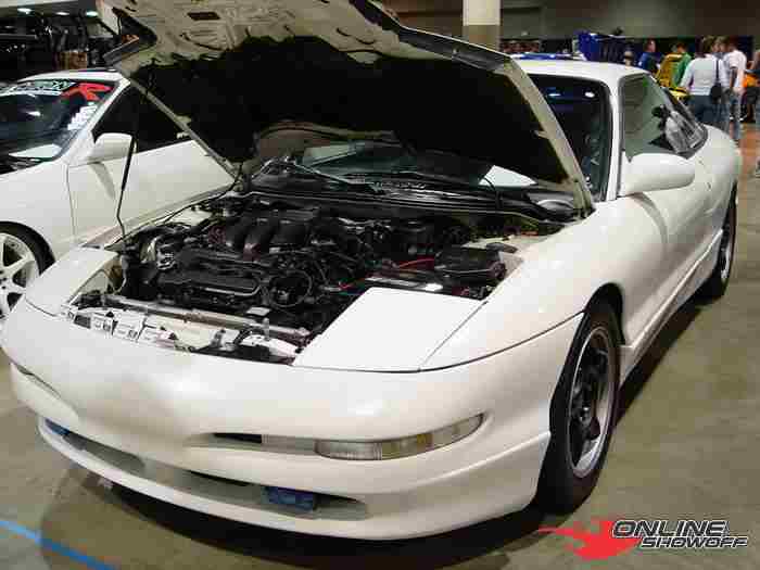 White Ford Probe coupe with hood open showing engine at indoor car show