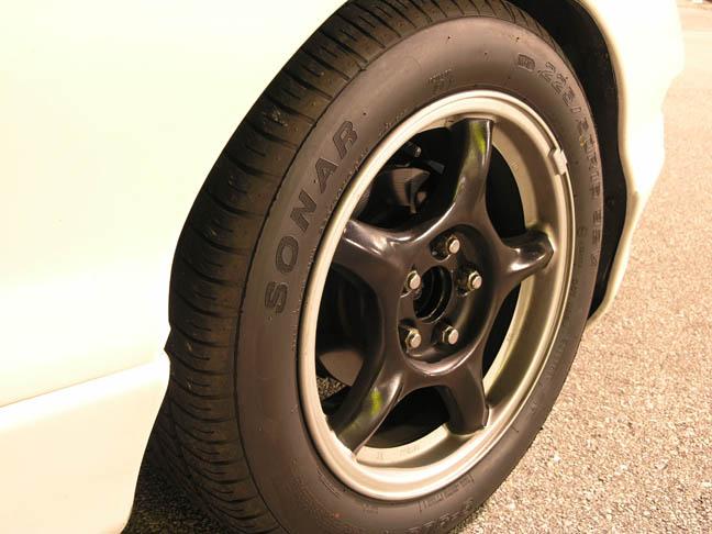 Gunmetal 5-spoke alloy wheel with SONAR tire on a white car