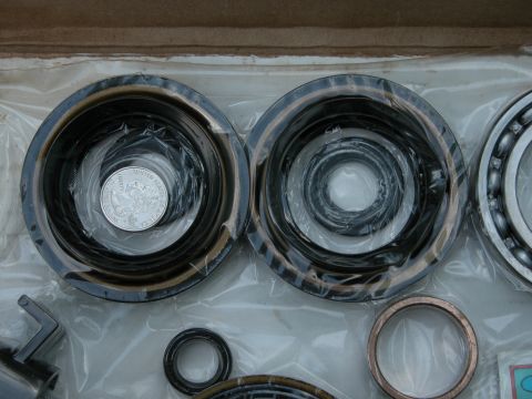 1990 Ford Bronco - A collection of automotive bearings and seals are shown, with a quarter placed inside one of the bearings for size reference.