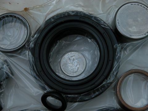 1990 Ford Bronco - Close-up of various automotive parts, including seals and bearings, with a US quarter for size reference.
