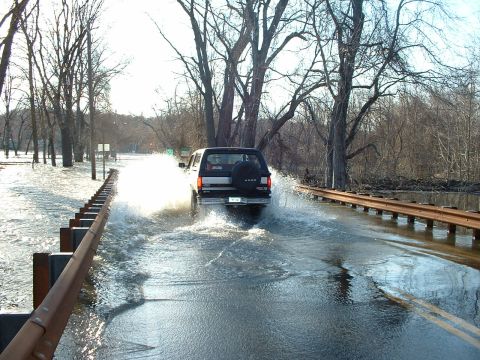 1993 Ford Bronco - A 1993 Ford Bronco navigates a flooded roadway, creating large splashes.