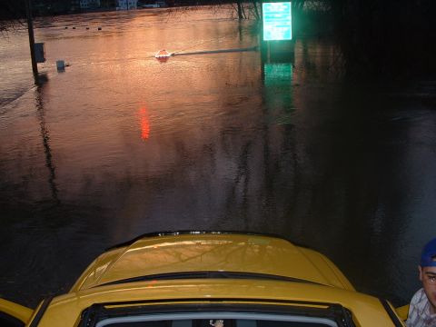 1993 Ford Bronco - A yellow SUV is partially submerged in floodwaters, with a glowing green sign visible in the distance.