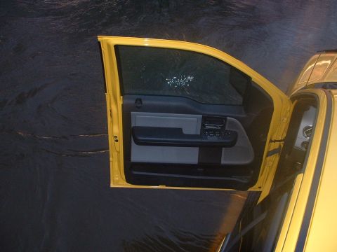 1993 Ford Bronco - The interior of a yellow truck is visible with the driver's side door open, revealing the door panel and part of the dashboard.