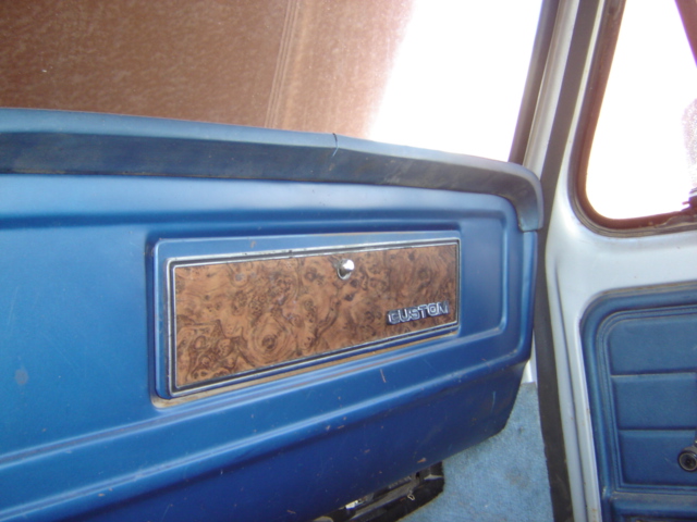 Interior door panel with woodgrain trim and 'CUSTOM' badge. Likely from an 80s Ford truck
