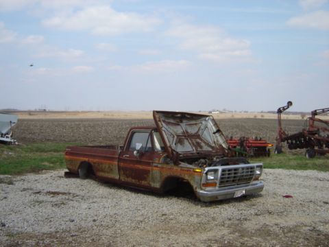 1992 Ford Bronco - A weathered pickup truck sits abandoned in a rural landscape, its hood ajar revealing the engine bay.