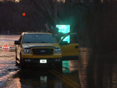 1993 Ford Bronco - A yellow Ford F-150 truck is partially submerged in floodwaters, with a person standing by the open door.
