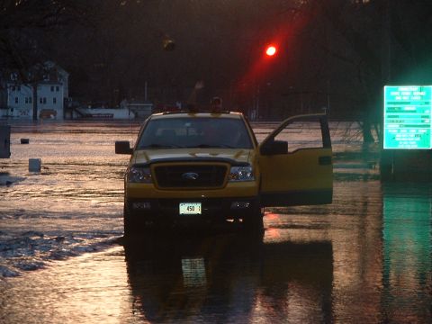 1993 Ford Bronco - A yellow Ford F-150 navigates through floodwaters with its door open, under a red traffic signal.