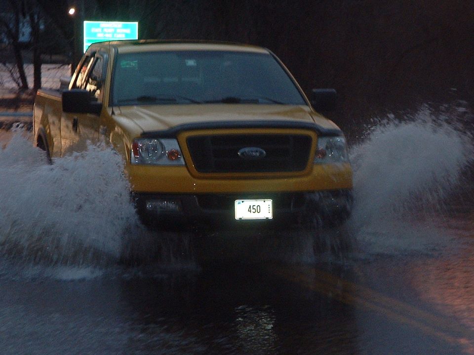 Yellow Ford F-150 truck with license plate 450 driving through flood water