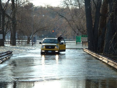 1993 Ford Bronco - A yellow Ford F-150 navigates a flooded road, with the driver's door ajar.