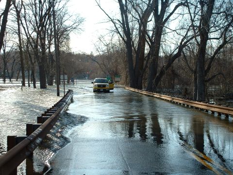 1993 Ford Bronco - A yellow pickup truck navigates a flooded road, with water reaching the vehicle's doors.