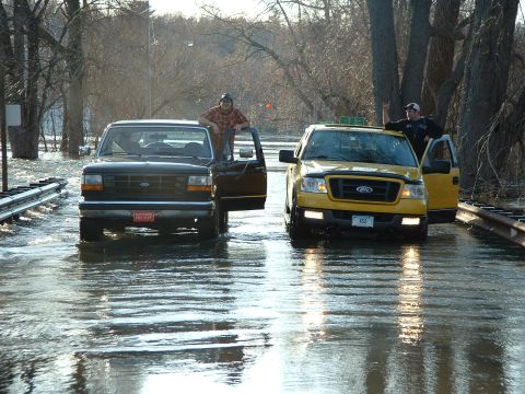 1993 Ford Bronco - A black Ford truck, possibly from the early 1990s, is seen driving through floodwaters with its doors open.