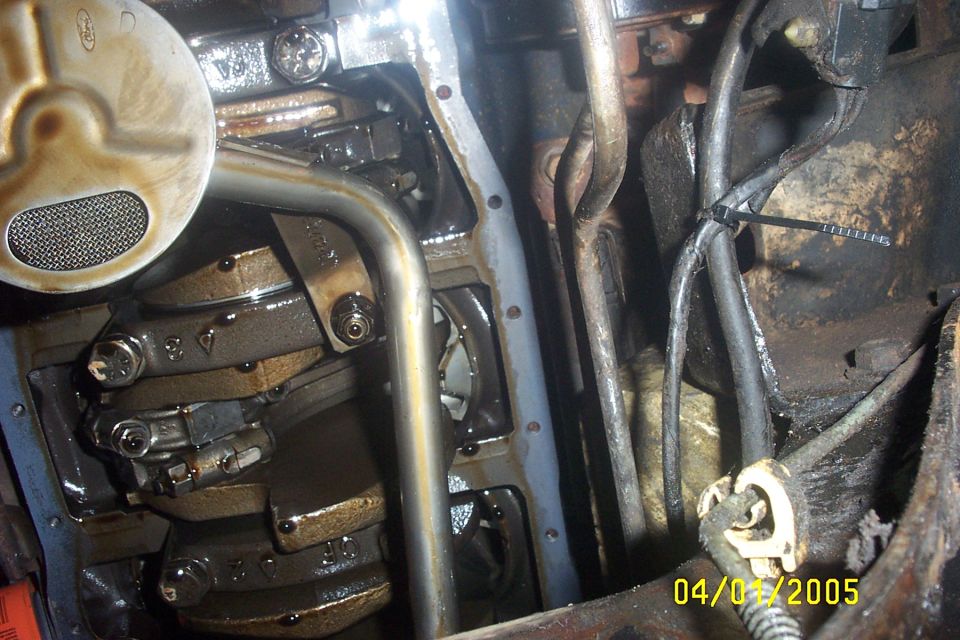 Engine oil pan removed, showing crankshaft and connecting rods. Oil pickup screen visible