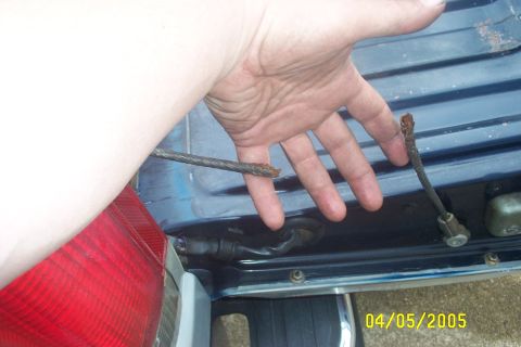 1979 Ford F-150 - A hand holds a broken cable near the rear of a blue vehicle.