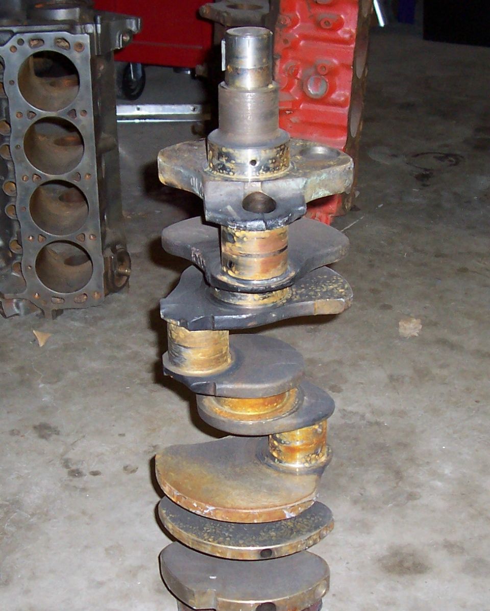 Used crankshaft and engine block on concrete floor