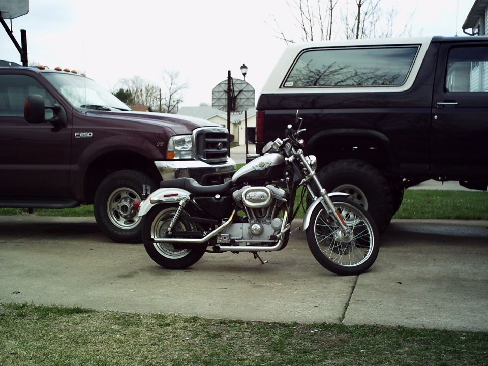 Motorcycle parked between a maroon Ford F-250 and a black Ford Bronco