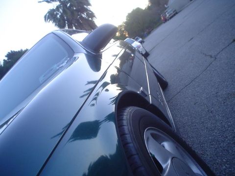 1993 Ford Taurus - A green 1993 Ford Taurus is seen from a low angle, parked on a cracked asphalt surface.