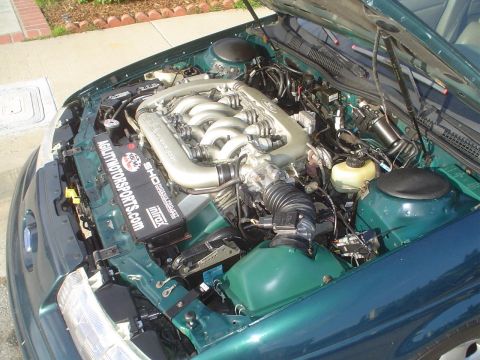 1993 Ford Taurus - The engine bay of a green 1993 Ford Taurus, identified by its SHO badging and distinctive intake manifold.
