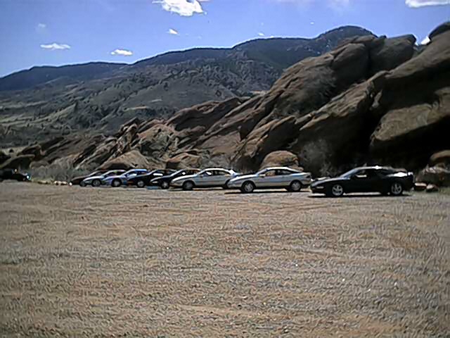 Silver 1996 Ford Probe parked in a line of cars with a rocky mountain backdrop