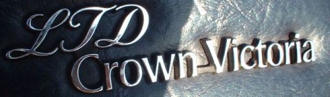 1984 Ford Crown Victoria LTD - Chrome emblems for LTD and Crown Victoria are shown against a dark, textured background.