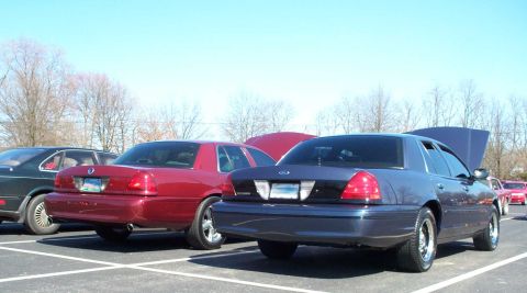 1998 Ford Crown Victoria - Two Ford Crown Victorias are parked side-by-side at an outdoor car meet.