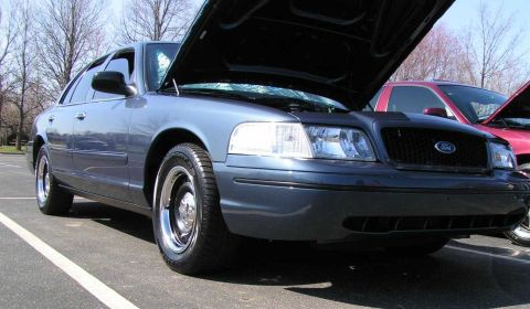 1998 Ford Crown Victoria - A blue 1998 Ford Crown Victoria is parked with its hood open at a car meet.