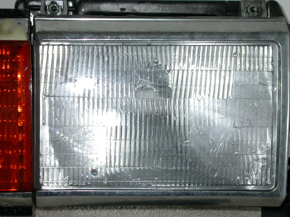 Close-up of chrome-trimmed rectangular headlight and amber marker lens on a 1990 Ford Bronco