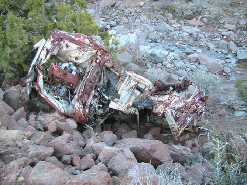 1978 Ford Bronco - This heavily damaged vehicle lies in a rocky, outdoor environment, its engine exposed.