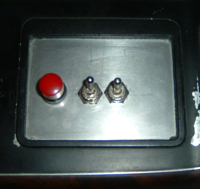 Aluminum panel with red push button and two chrome toggle switches in black bezel