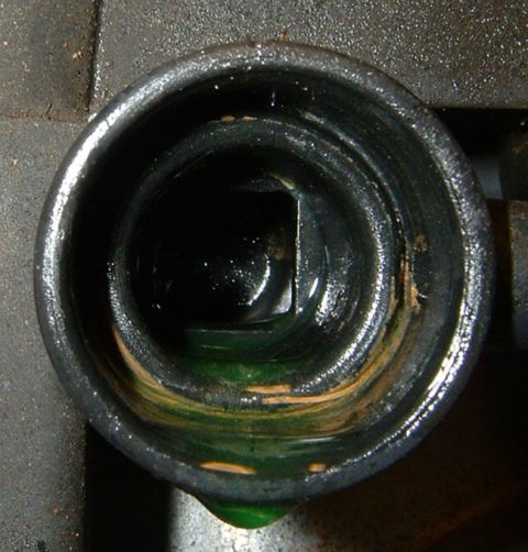 1987 Ford Bronco - The radiator cap opening shows some green coolant and rust buildup inside the neck.