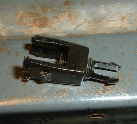 1987 Ford Bronco - A close-up view of a black plastic radiator clip with a split end, positioned on a rusty surface.