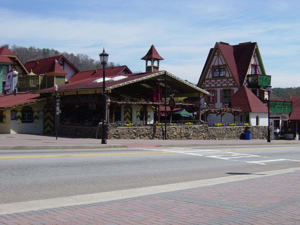Street view of buildings with red roofs and stone walls, some with balconies